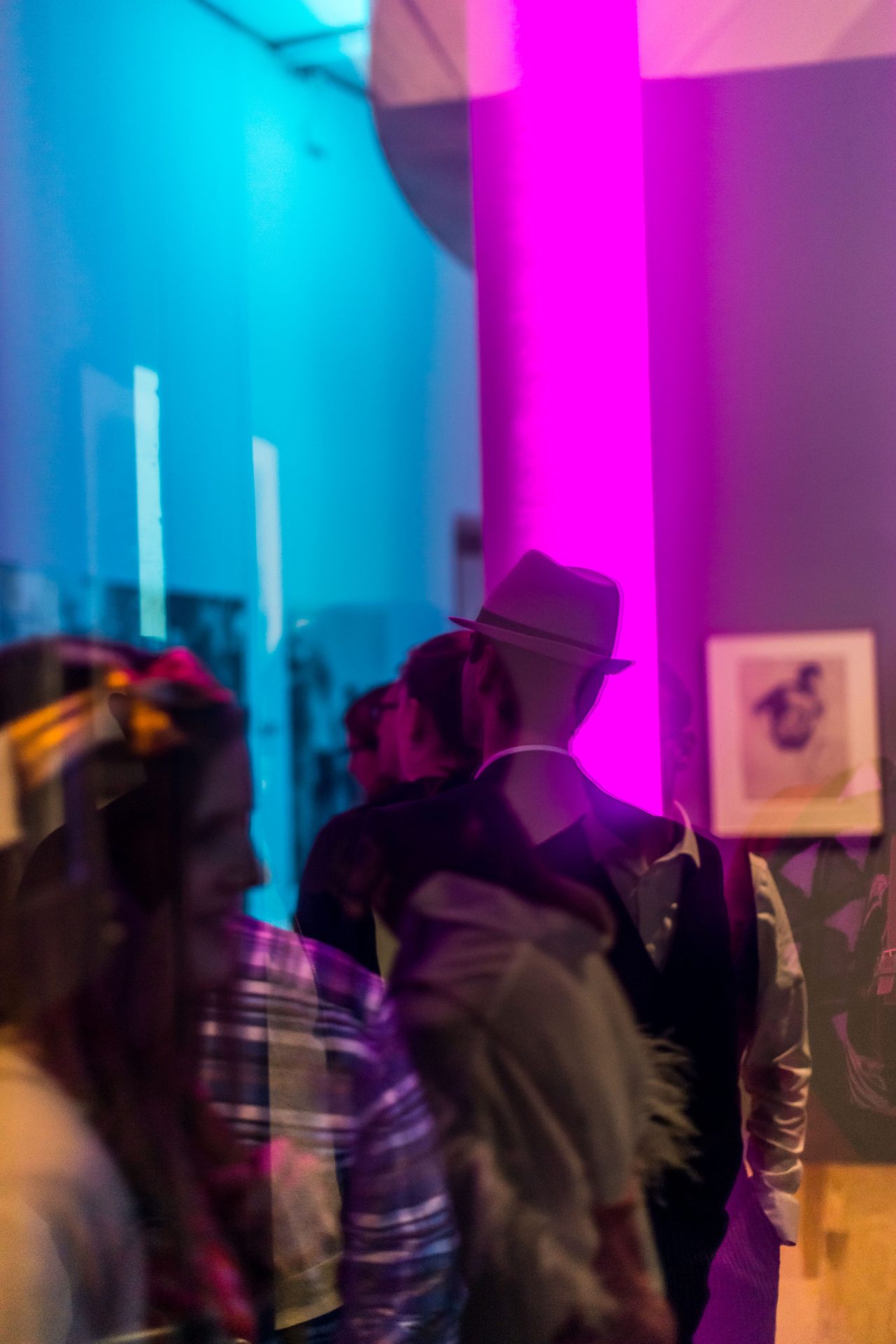 Menschen unterhalten sich in einem modernen, bunten Raum mit pinker Beleuchtung.