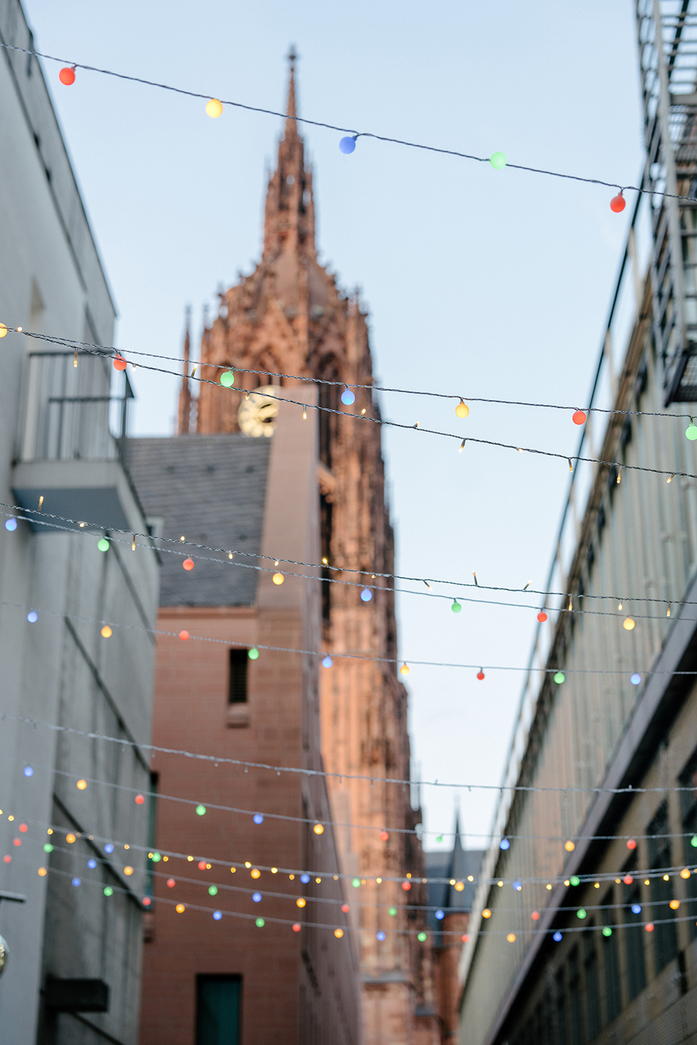 Blick auf einen Kirchturm, umgeben von bunten Lichtern, die eine festliche Stimmung erzeugen.