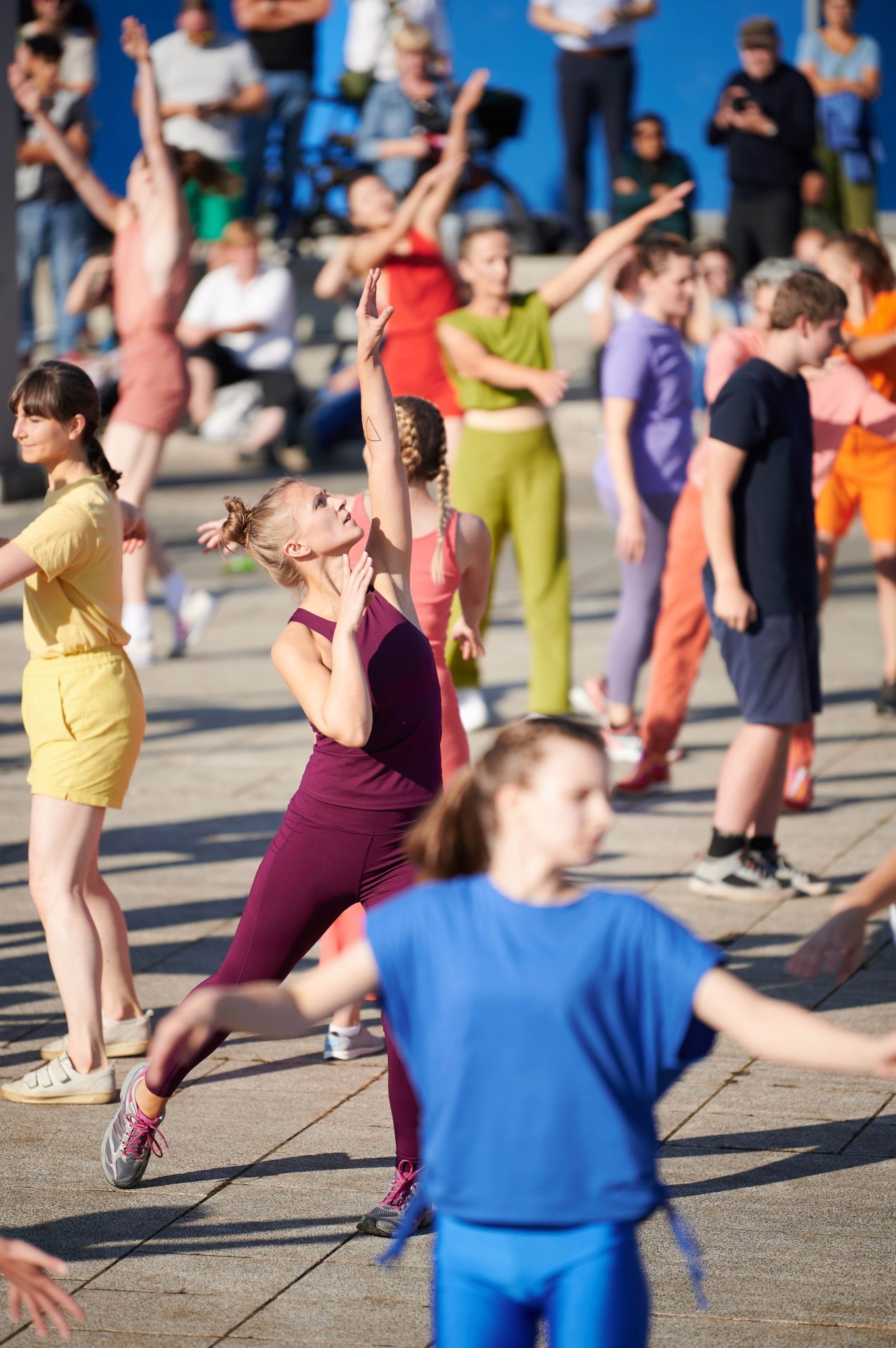Tanzende Gruppe in bunten Outfits, harmonisch in Bewegung im Freien.