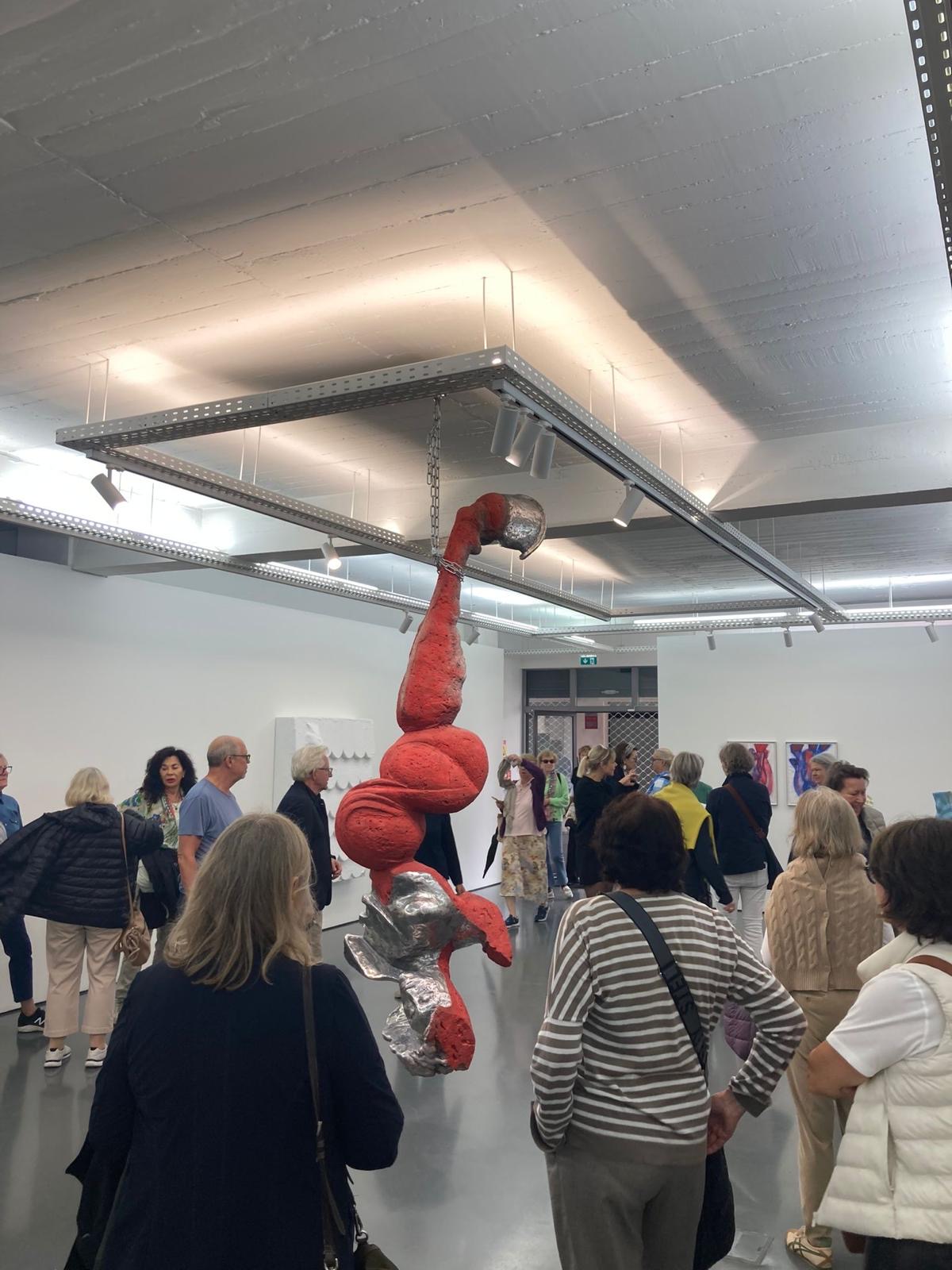 Eine futuristische Skulptur in einem Kunstmuseum mit Besuchern, die die Installation bewundern.